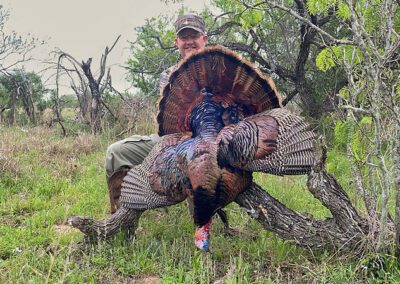 Man stands beside a turkey, showcasing their connection to nature and wildlife.